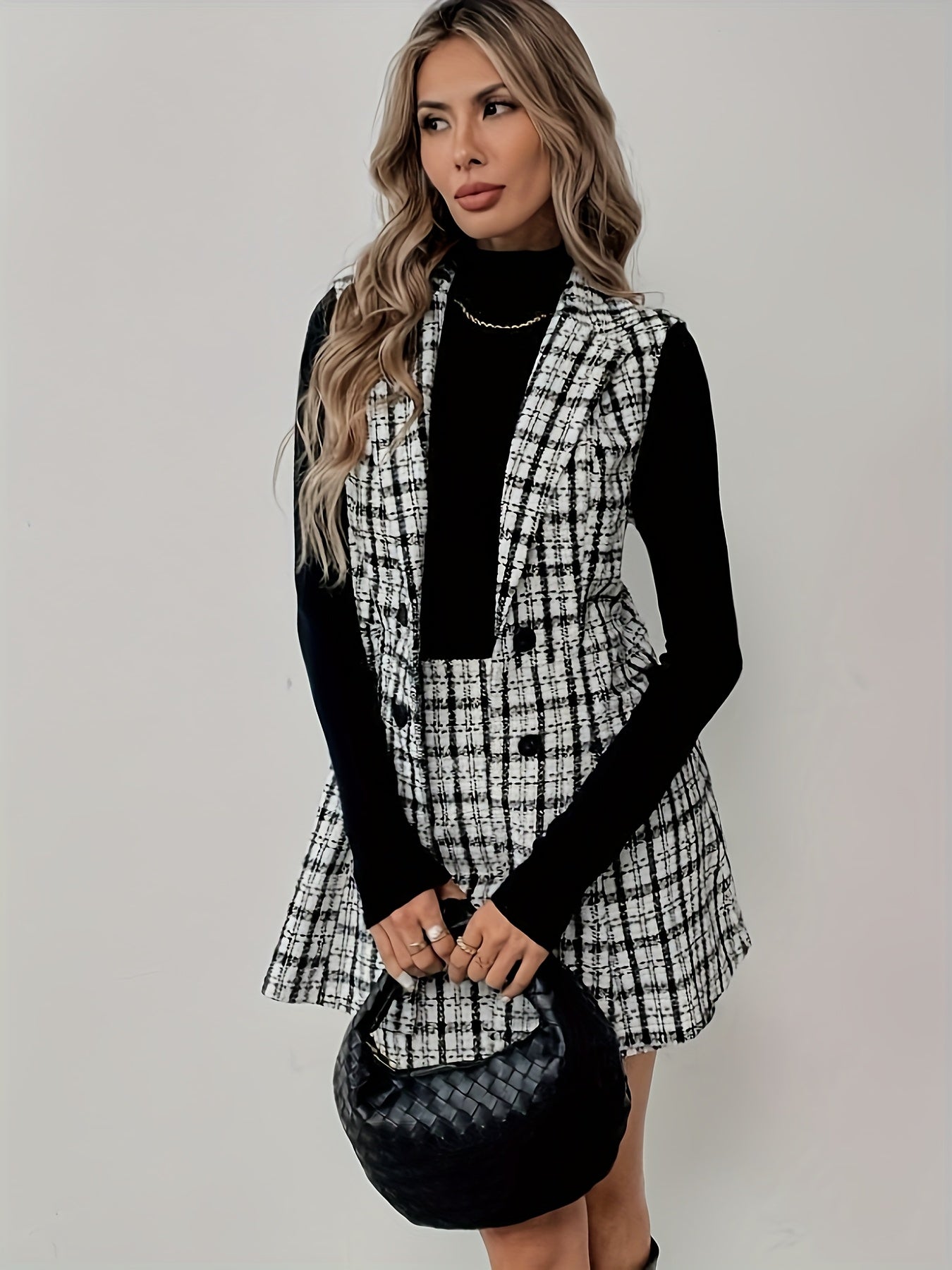 Ensemble motif carreau blanc et noir deux pièces blazer sans manches et d'une jupe courte, parfait pour une tenue professionnelle élégante.
